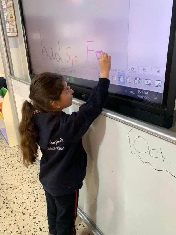 A young student writes on an interactive smart board