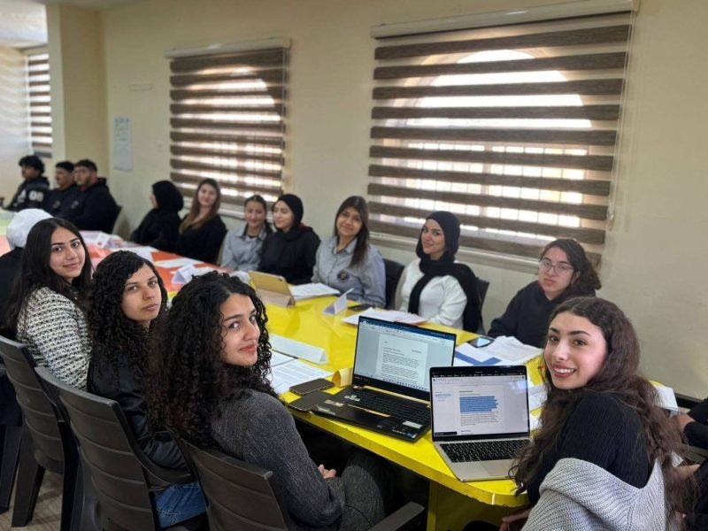 Secondary students work together on laptops around a table