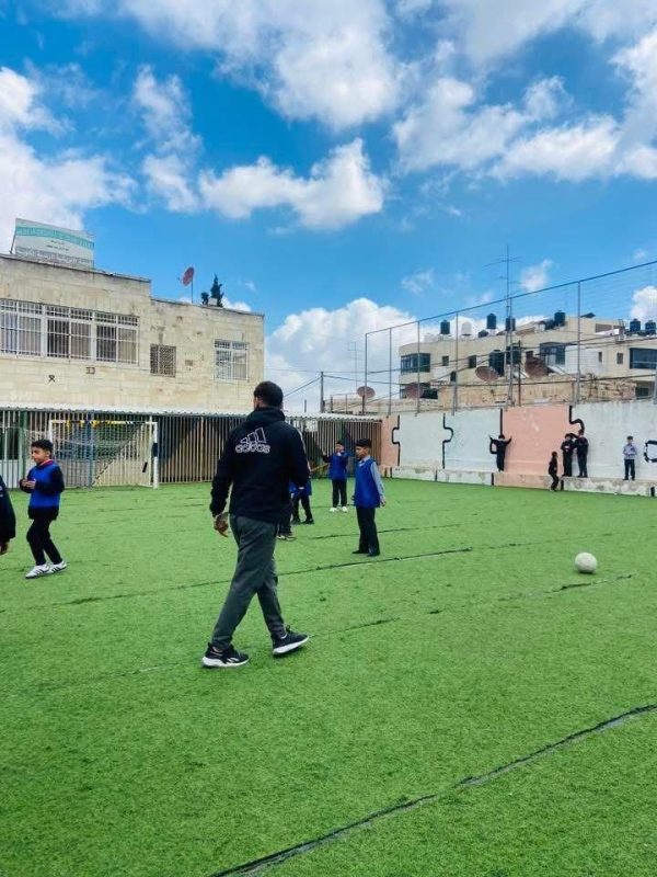 A teacher leads a physical education lesson on the artificial-grass pitch