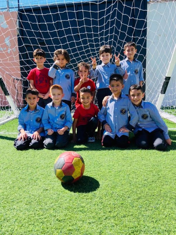 فريق كرة القدم للطلاب أمام المرمى وكرة على أرض الملعب